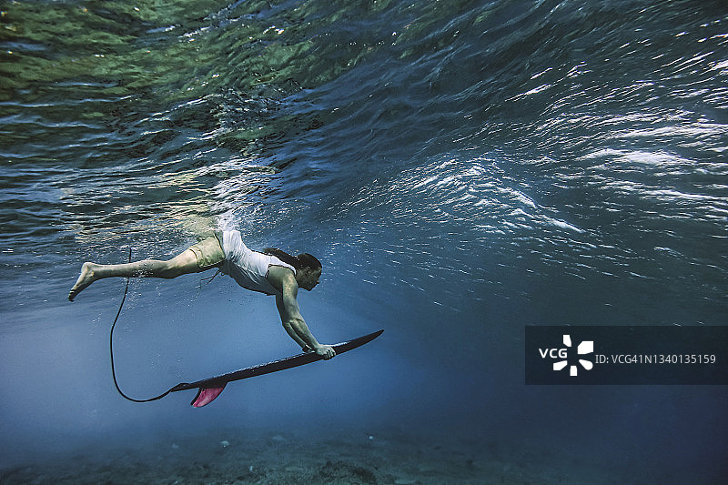 在马尔代夫水下潜水时拿着冲浪板的男性冲浪者图片素材