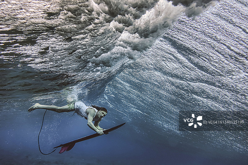 在马尔代夫水下潜水时拿着冲浪板的男性冲浪者图片素材
