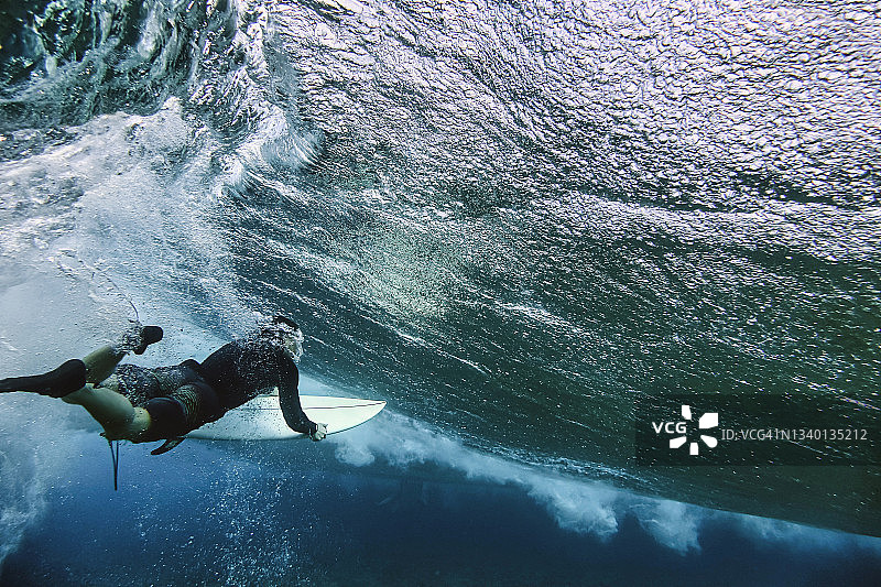 在马尔代夫水下潜水时拿着冲浪板的男性冲浪者图片素材
