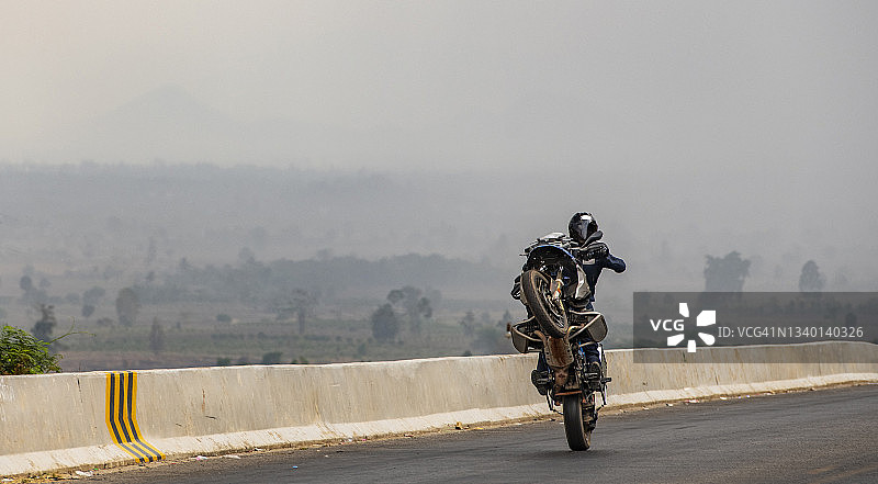 男人在柬埔寨的重型探险自行车上表演翘头图片素材