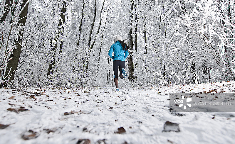 在德国下萨克森州结霜的森林中奔跑的女人图片素材