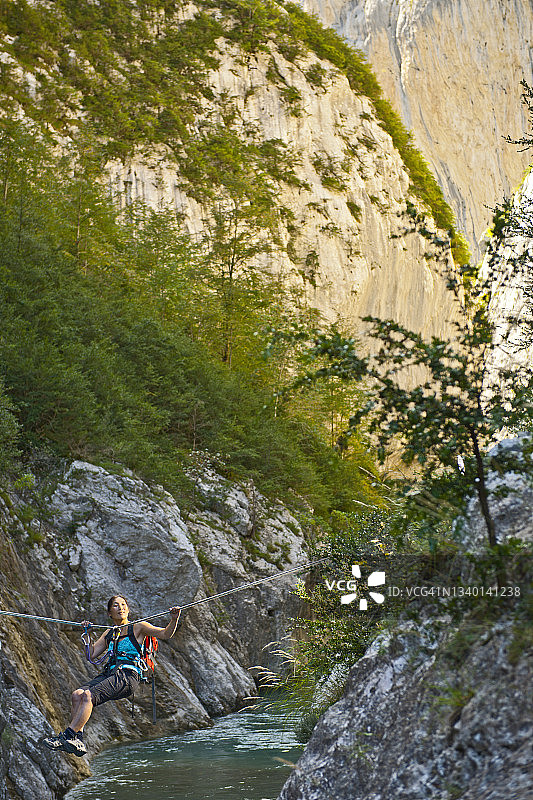 女人在韦尔东峡谷通过高空滑索过河图片素材