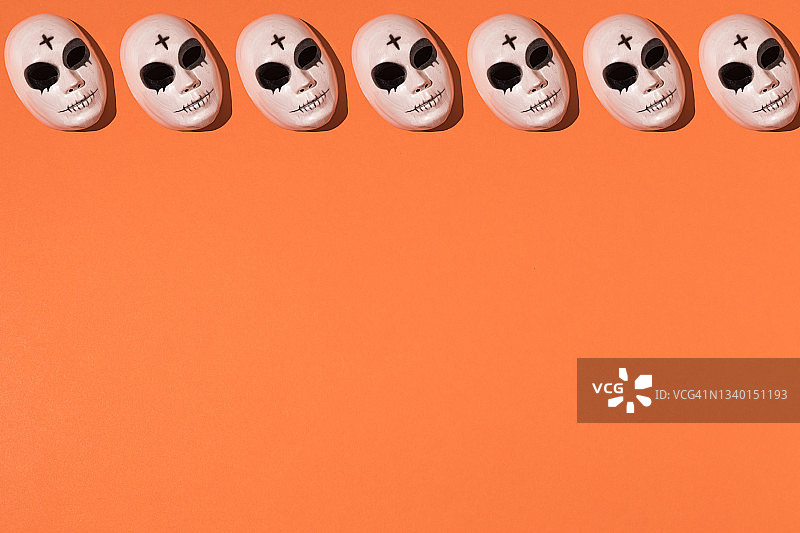 重复万圣节杀手面具图案，前额带十字，橙色背景上部线条有明显的黑眼圈。万圣节庆祝概念。图片素材