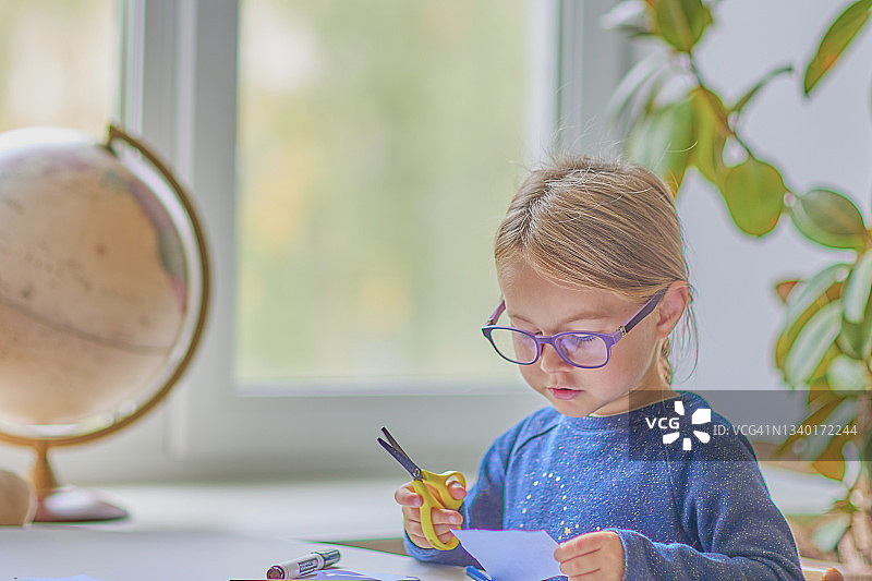 女孩坐在桌旁用铅笔和记号笔画画；做作业；发展；孩子不看镜头，近距离图片素材