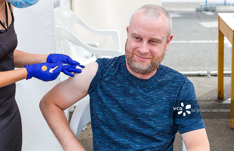中年男子在户外疫苗接种中心接种新冠疫苗图片素材