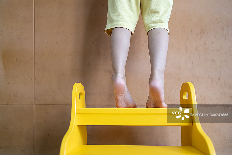 踮着脚站在黄色楼梯上的孩子图片素材