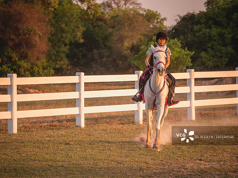 在农场享受骑马乐趣的年轻亚洲女孩，在牧场进行骑马训练图片素材
