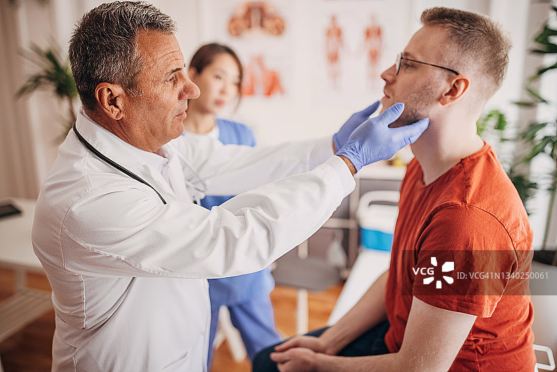 医生在诊所检查病人的腺体，护士在病历上做记录图片素材