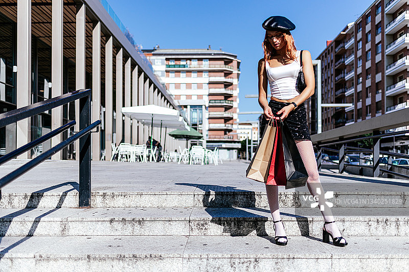 手提购物袋站在楼梯台阶上的漂亮女人图片素材