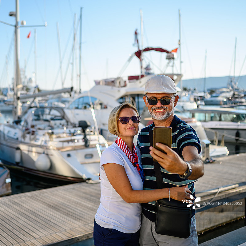 一对中年夫妇在港口用智能手机拍照图片素材