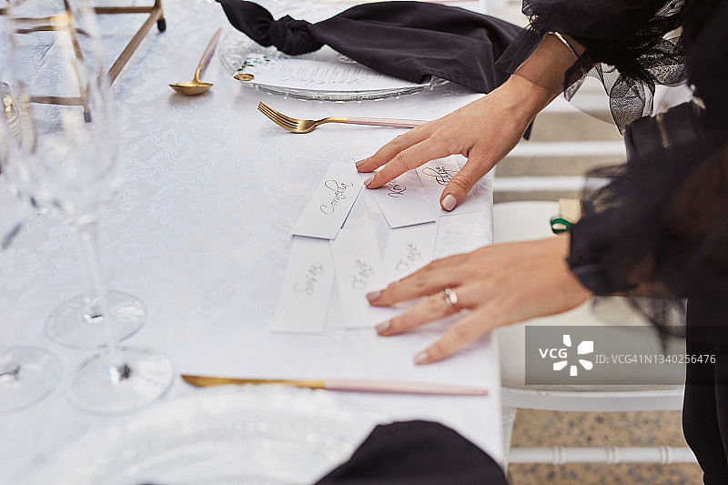 女子在婚礼招待会上用席位卡装饰桌子图片素材