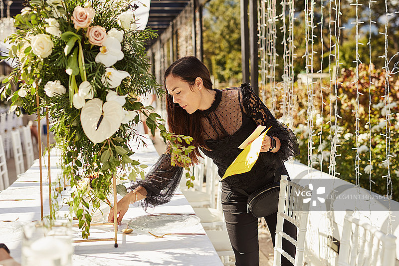 年轻女人装饰餐桌，准备婚礼招待会图片素材