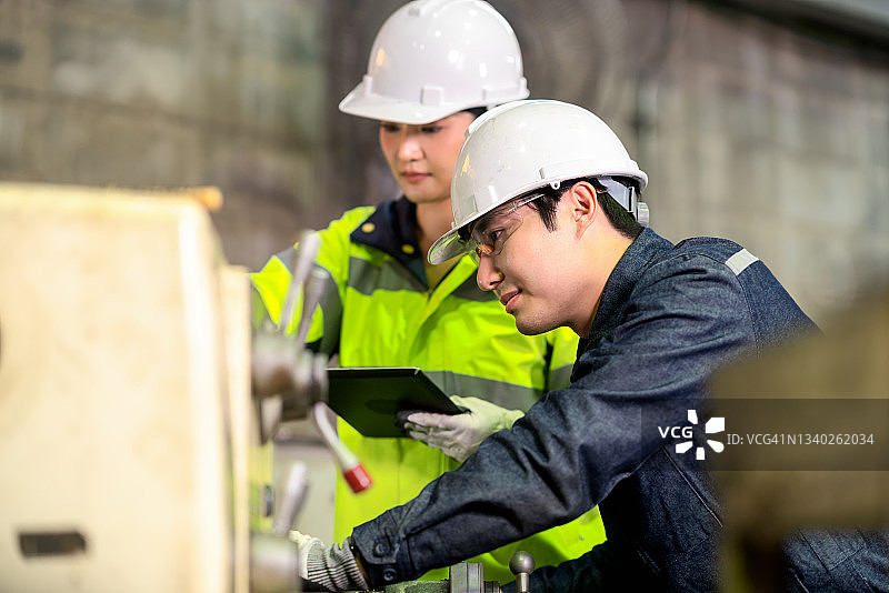 金属工厂中，车床操作员向他的培训师展示工作步骤，工厂和制造概念图片素材