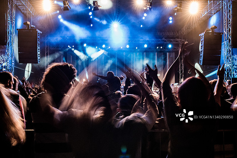 粉丝们举起手臂享受音乐会，人们在露天音乐节上图片素材