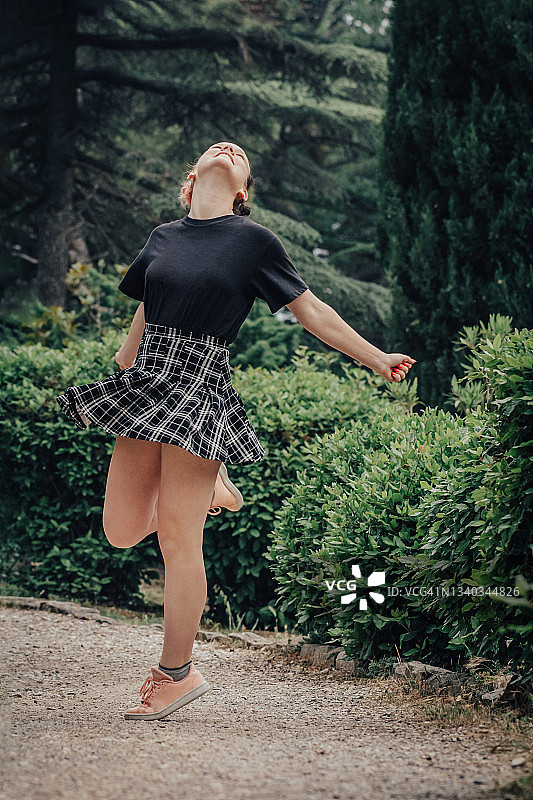 户外单腿旋转的快乐少女图片素材