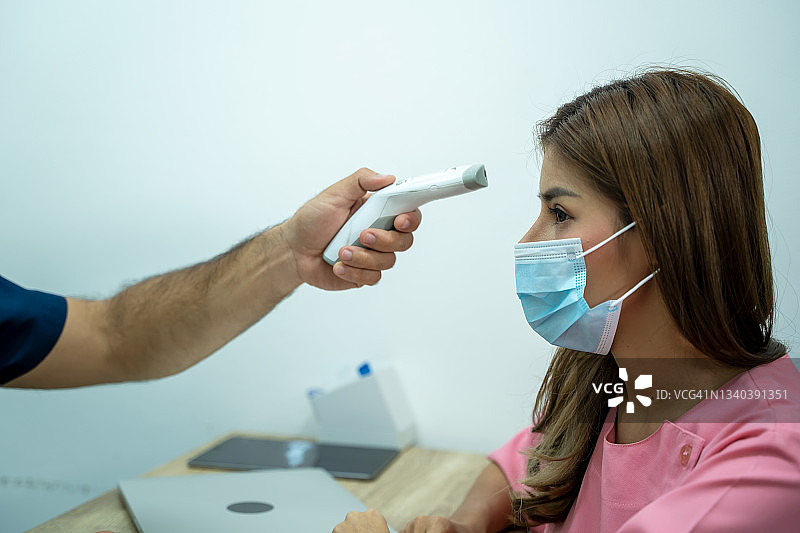 医生使用红外温度计设备检查额头温度，检查新冠病毒。图片素材