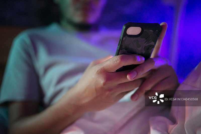 青年使用带有社交媒体排毒屏幕的笔记本电脑，并在晚上失眠时使用手机图片素材