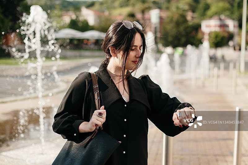 年轻女人查看手表上的时间图片素材