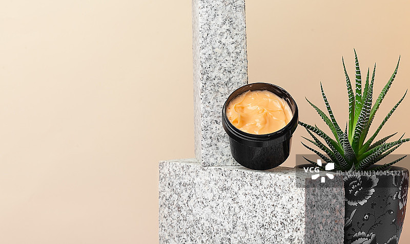 米色背景上紫色罐中的橙色身体和面部皮肤护理产品图片素材