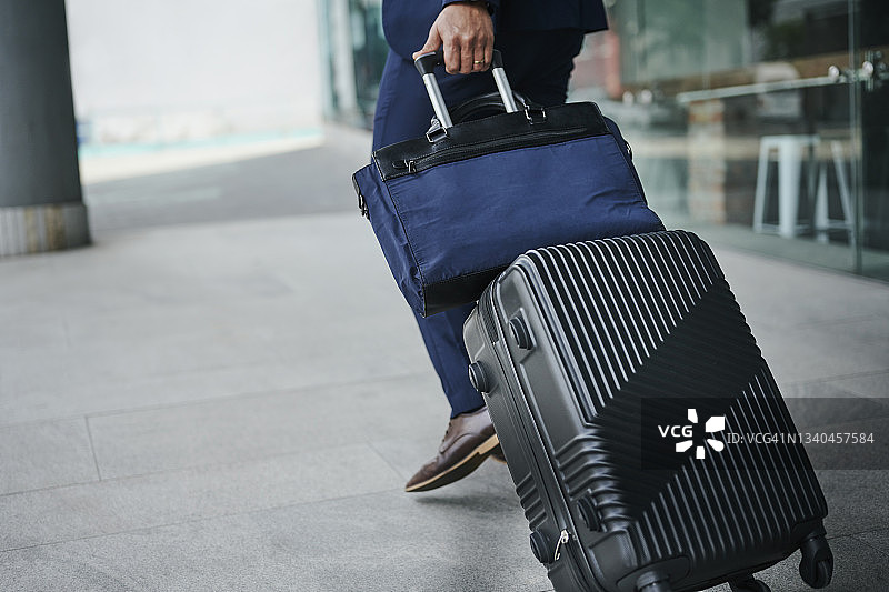 拉着行李箱和包在户外行走的商人图片素材