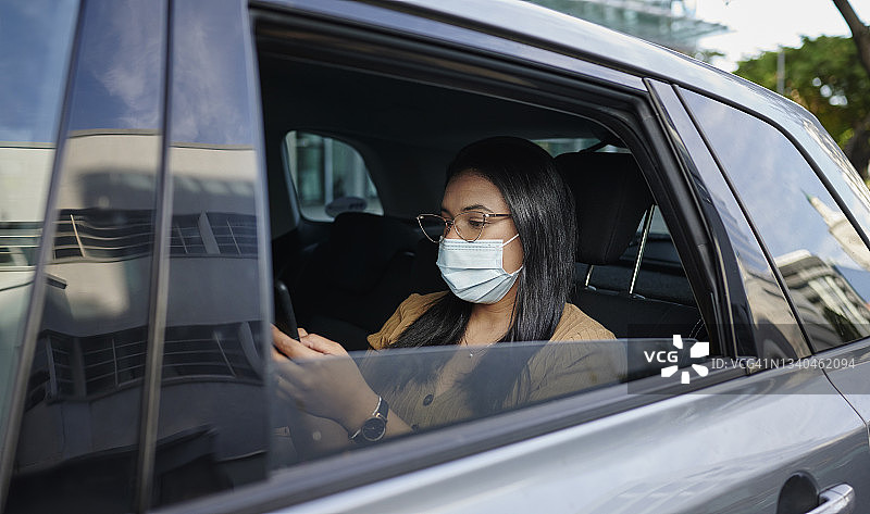 戴着口罩的女商人在出租车上发短信图片素材