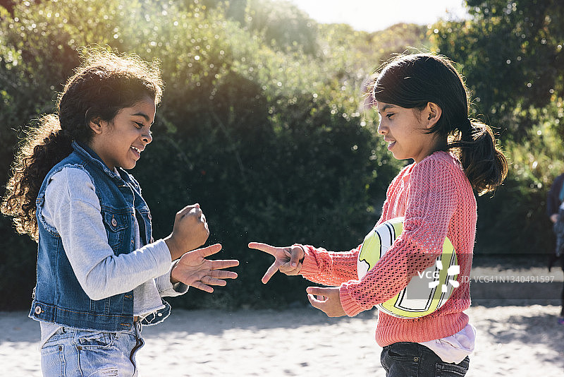 微笑着在阳光明媚海滩玩剪刀石头布的兄弟姐妹图片素材
