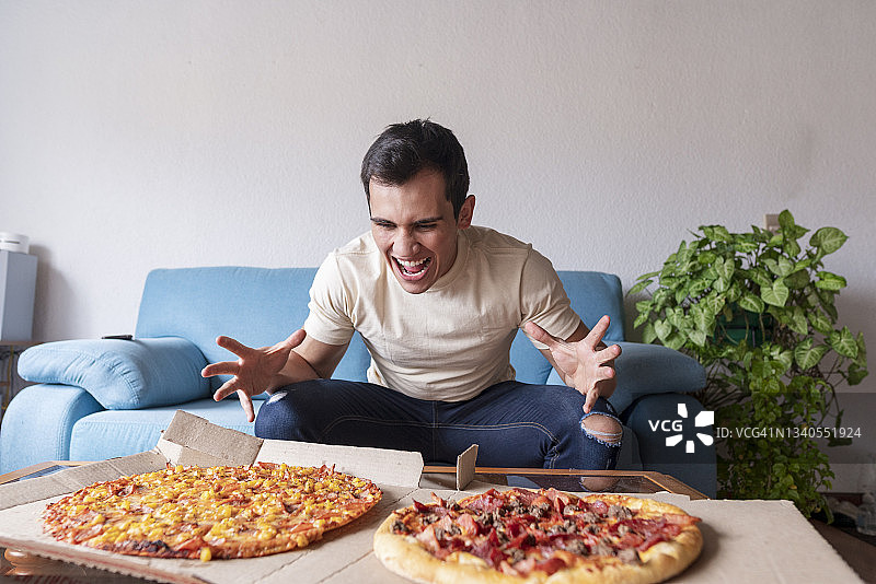 看到两盒披萨时，客厅里露出惊讶表情的拉丁男人图片素材