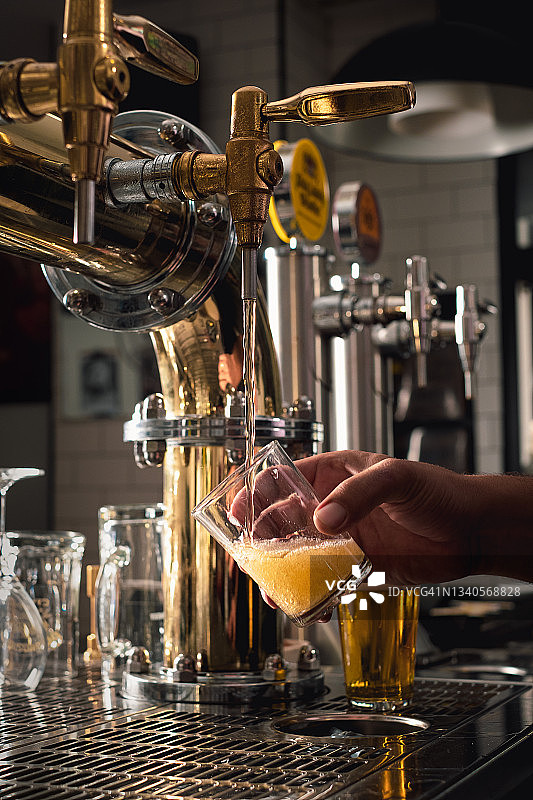 在酒吧，酒吧招待从水龙头接啤酒图片素材