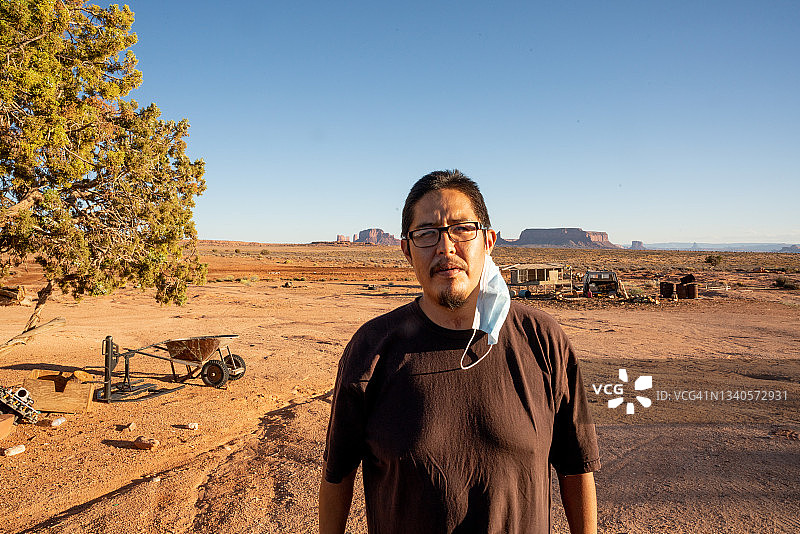 在阳光明媚的午后，一位二十多岁的年轻纳瓦霍族男子戴着新冠病毒口罩，以减缓疫情传播图片素材