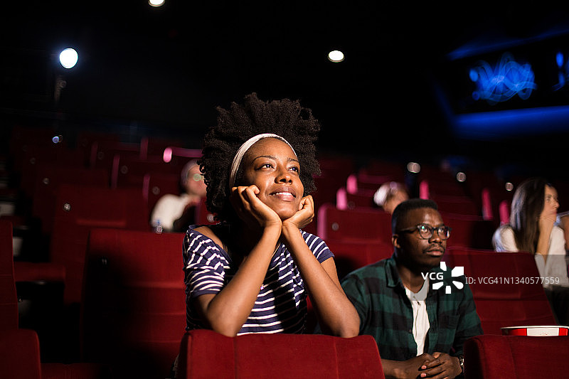 非裔美国年轻女子对电影院的电影感到高兴图片素材