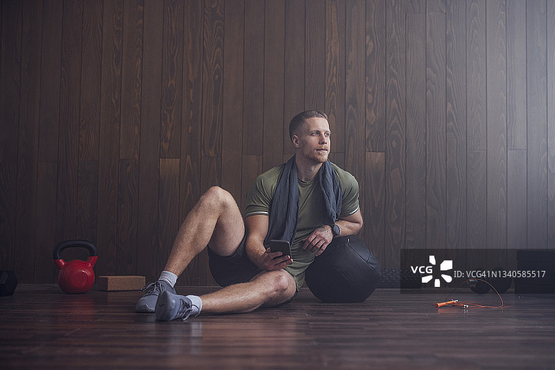 英俊的白人男子在健身房使用手机图片素材