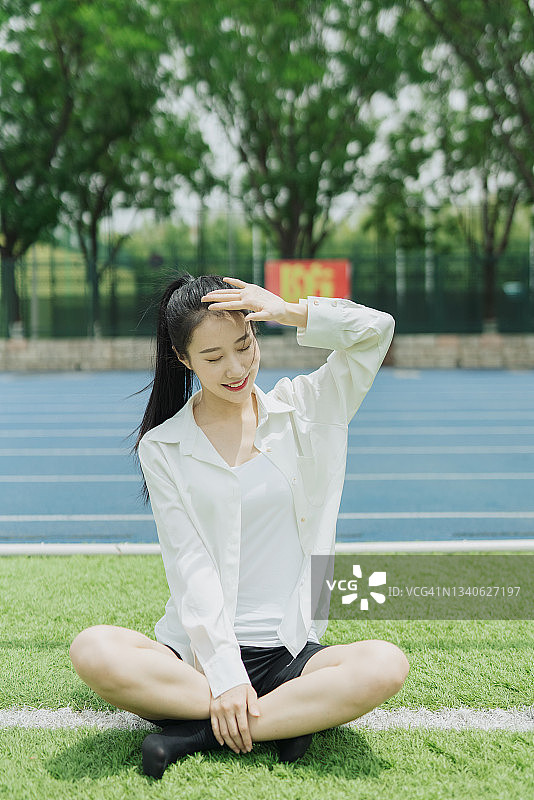 草坪上穿白衬衫的亚洲女大学生图片素材
