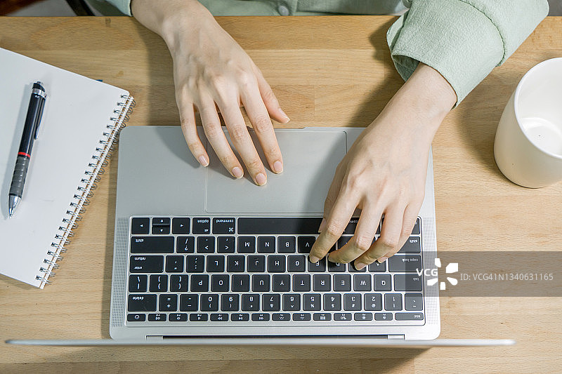 女性在笔记本电脑上打字的俯视图图片素材