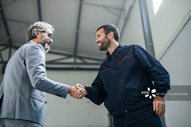 快乐的检查员与体力劳动者握手图片素材