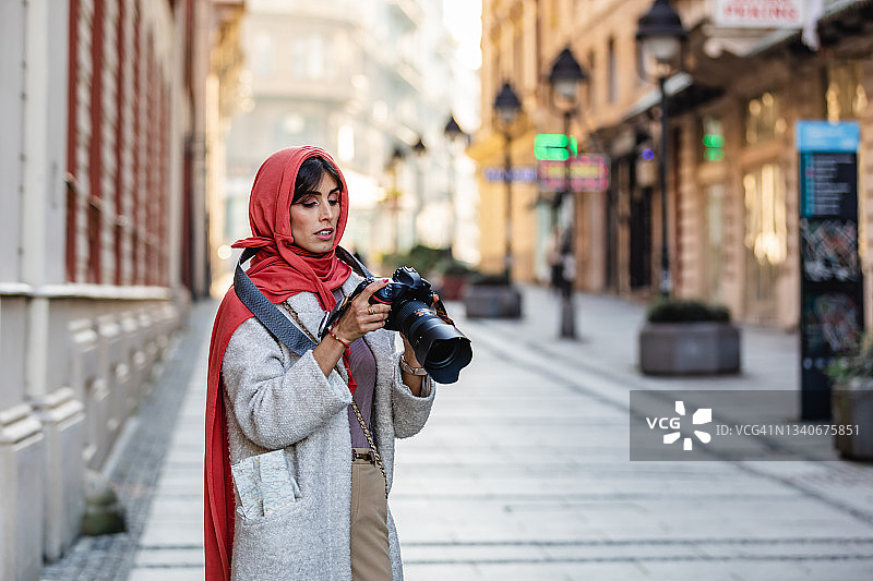 旅行并手持数码相机拍照的中年穆斯林妇女图片素材