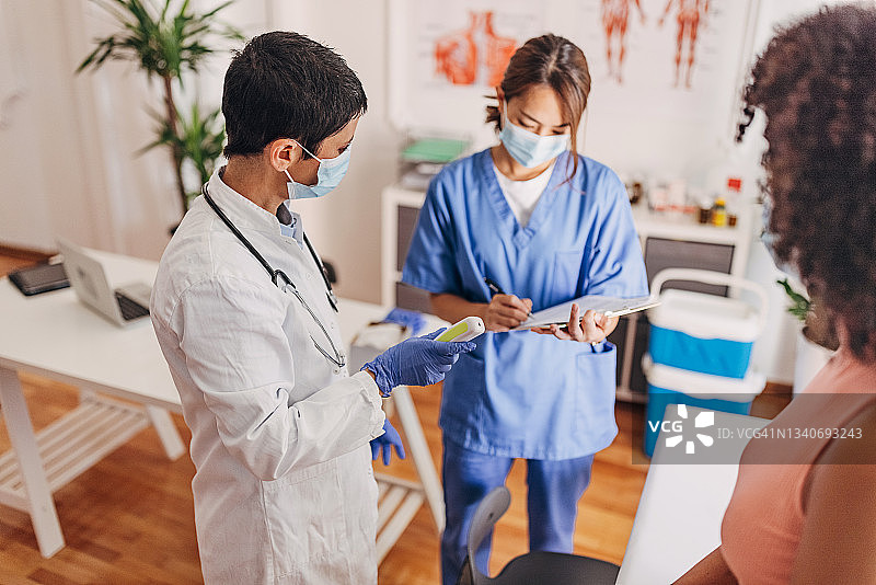 医生在新冠诊所检查病人，测量体温图片素材