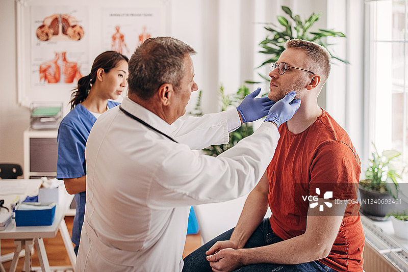 医生在诊所检查病人的腺体，护士在病历上做记录图片素材