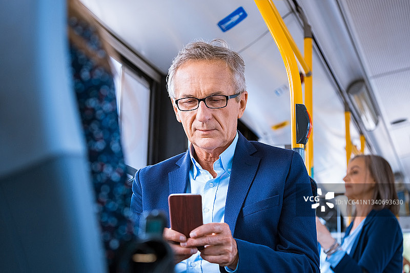 在公交车上使用手机的年长商人图片素材
