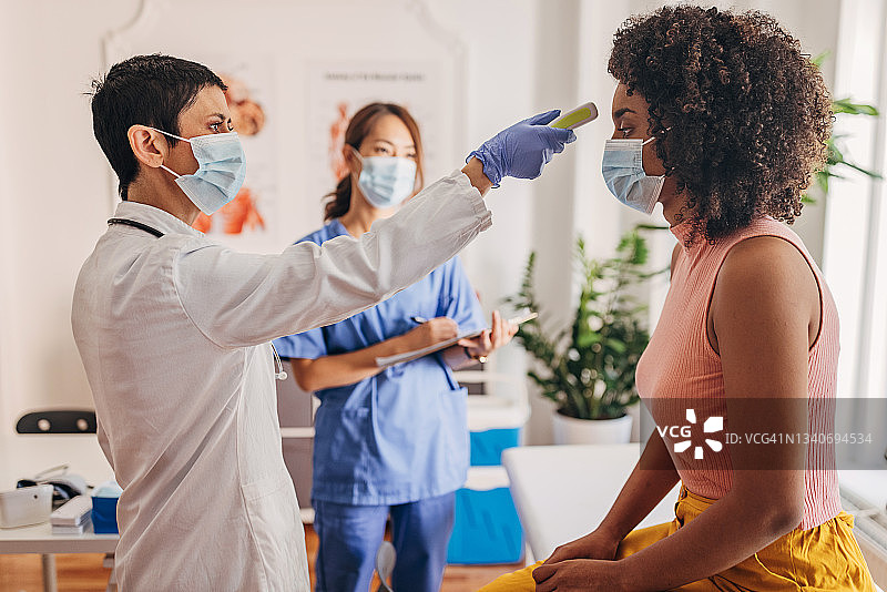 医生在新冠诊所检查病人，测量体温图片素材
