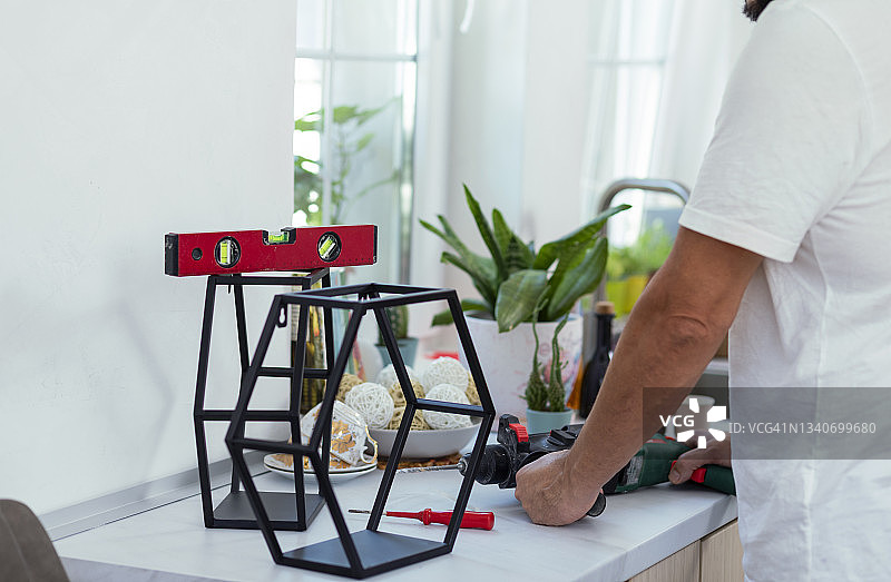 中年男人在厨房安装墙壁置物架图片素材