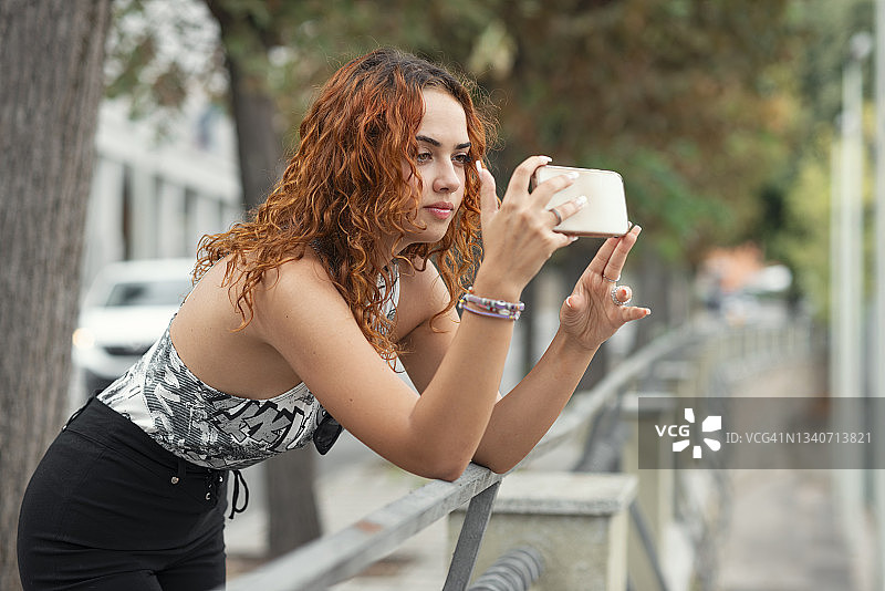 红发混血女人用手机拍照图片素材