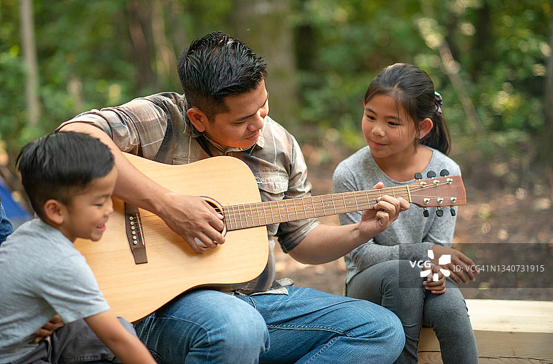 爸爸在露营时为孩子们弹吉他图片素材