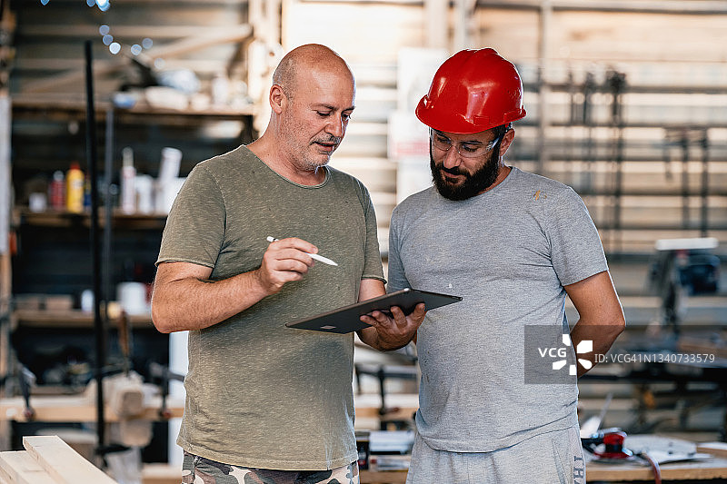 中年建筑师在木工车间向木匠讲解项目图片素材
