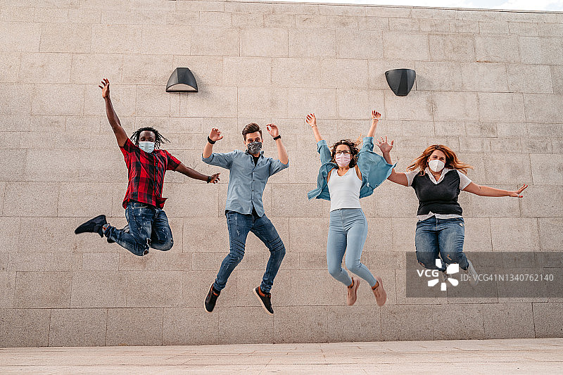 在墙前跳跃的快乐朋友们图片素材