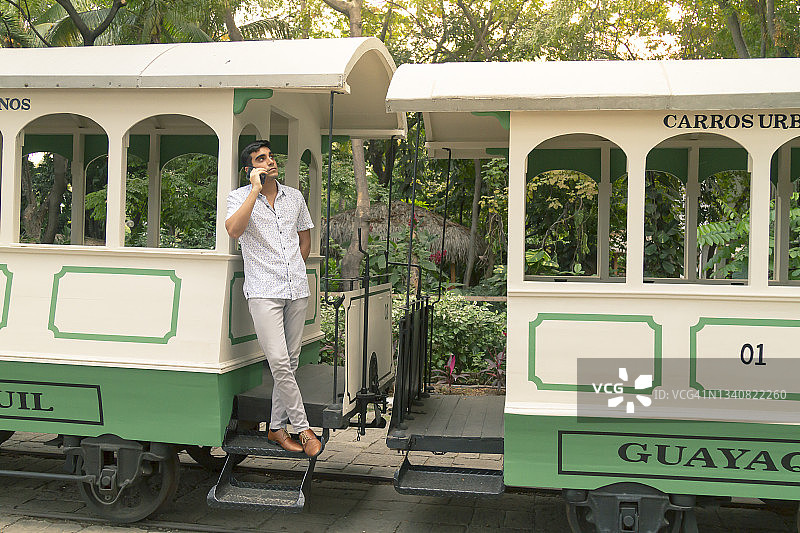 在厄瓜多尔瓜亚基尔老城区使用5G技术旅行并通过智能手机/手机交谈的年轻拉丁裔男子肖像图片素材