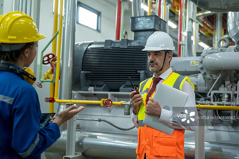 现代火力发电厂，工业工人与经理讨论工业项目。图片素材