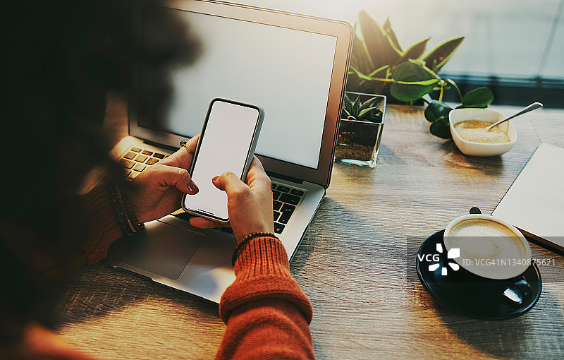 女商人一边在咖啡店工作一边使用智能手机图片素材