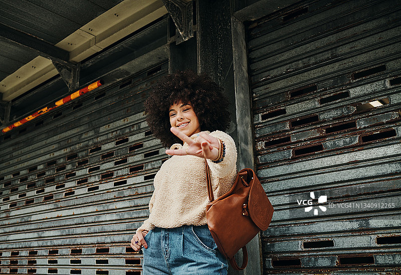 年轻女子在城市中做出和平手势图片素材