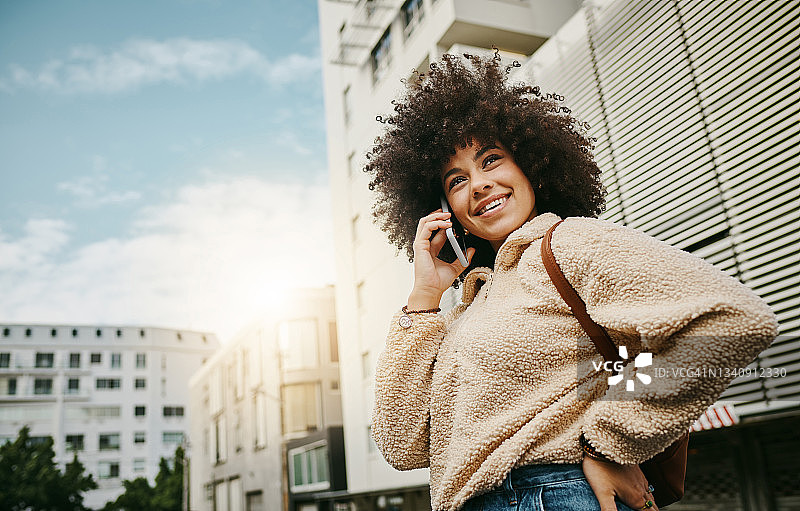 在城市里，一位美丽的年轻女子用手机通话的照片图片素材