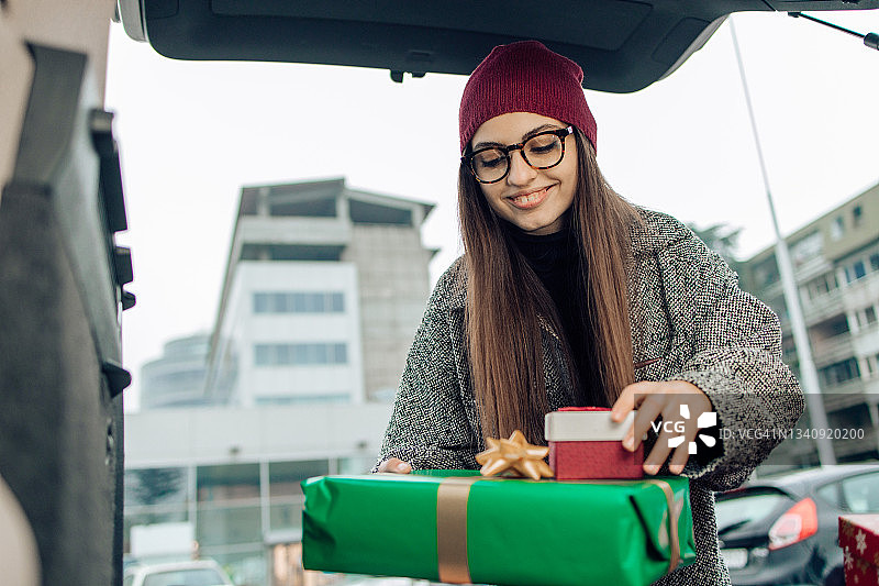 把购买的圣诞礼物装进汽车后备箱的年轻女子肖像图片素材